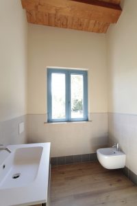 Casa di campagna - interno - bagno per gli ospiti con tetto in legno e luminosissima finestra di colore blu