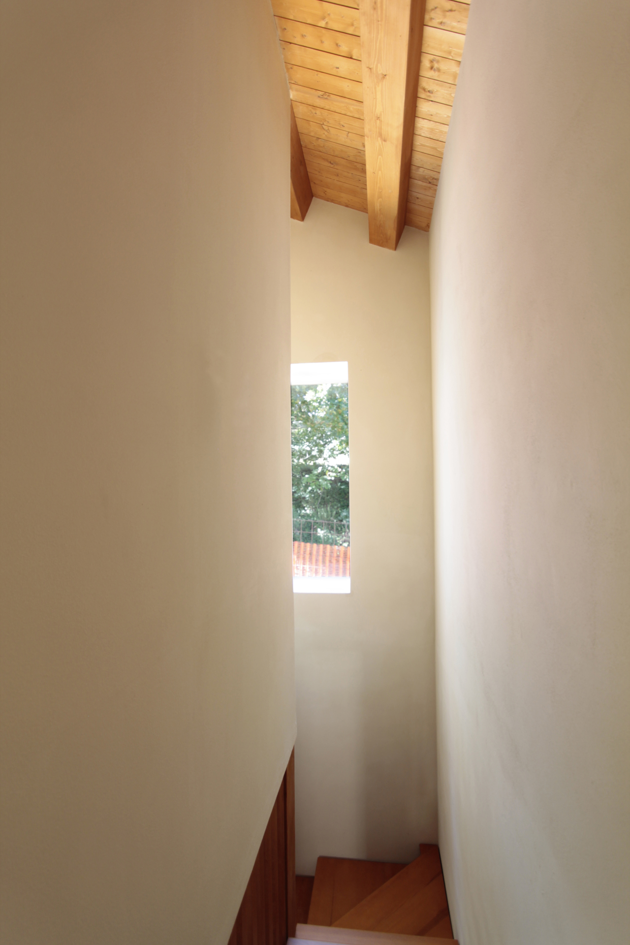 Casa di campagna - interno - vano scala interno luminoso con scala in legno e tetto in legno e pareti con spigoli arrotondati in intonaco a calce