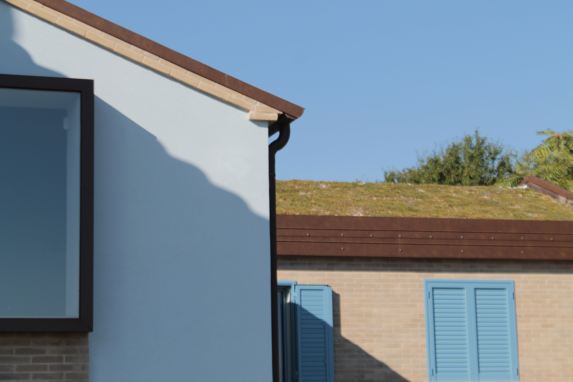 Casa di campagna - esterno - tetto giardino - finestra baywindow - intonaco azzurro e finestre blu - mattina di sole