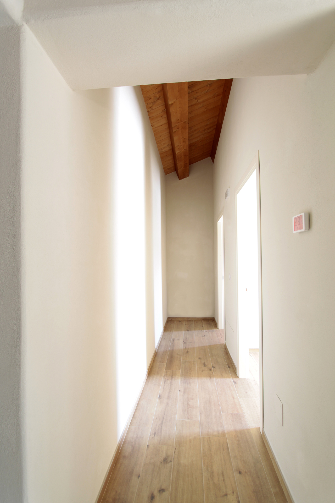 Casa di campagna - interno - corridoio luminoso con tetto in legno e pareti con spigoli arrotondati in intonaco a calce